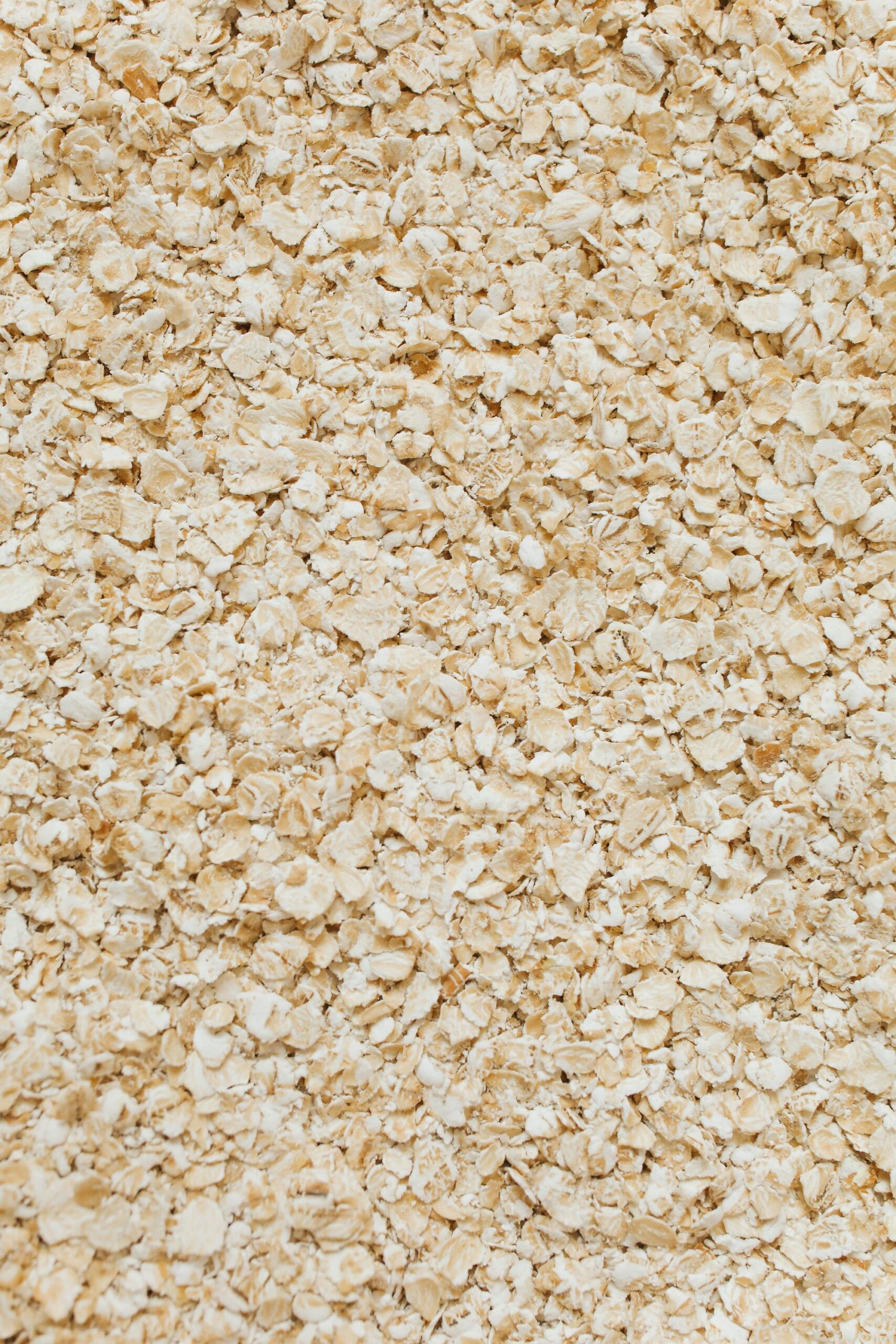 A detailed texture of raw oatmeal grains in a close-up vertical shot.